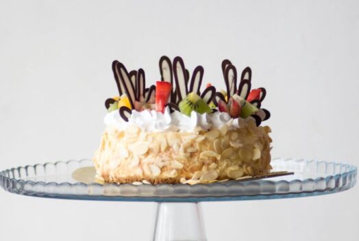 Voćna torta ukrašena šlagom, mrvicama bele čokolade i kivijem